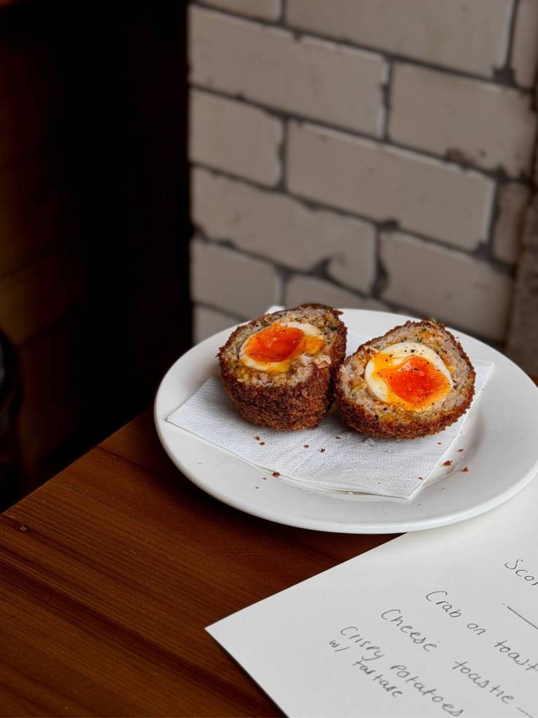 scotch eggs on white plate on table, one of the bar snacks at the trof