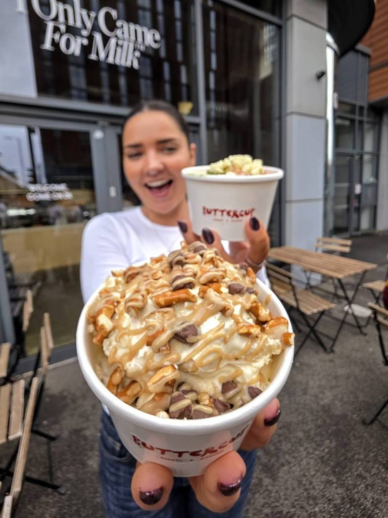 buttercup employee holding two pots of banana pudding outside of ancoats general store