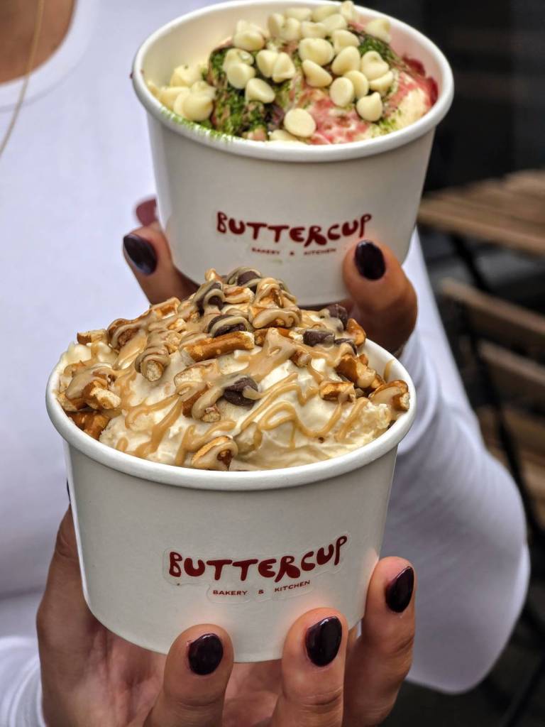 two pots of buttercup banana pudding with toppings such as pretzel the other white chocolate drops and raspberry