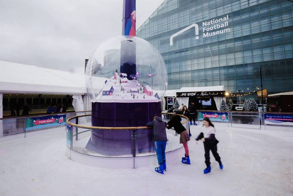 snow globe in centre of skate manchester ice rink next to national football museum, cathedral gardens with children skating around globe
