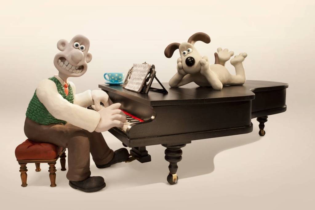 wallace sat on stool by piano and gromit lying across piano
