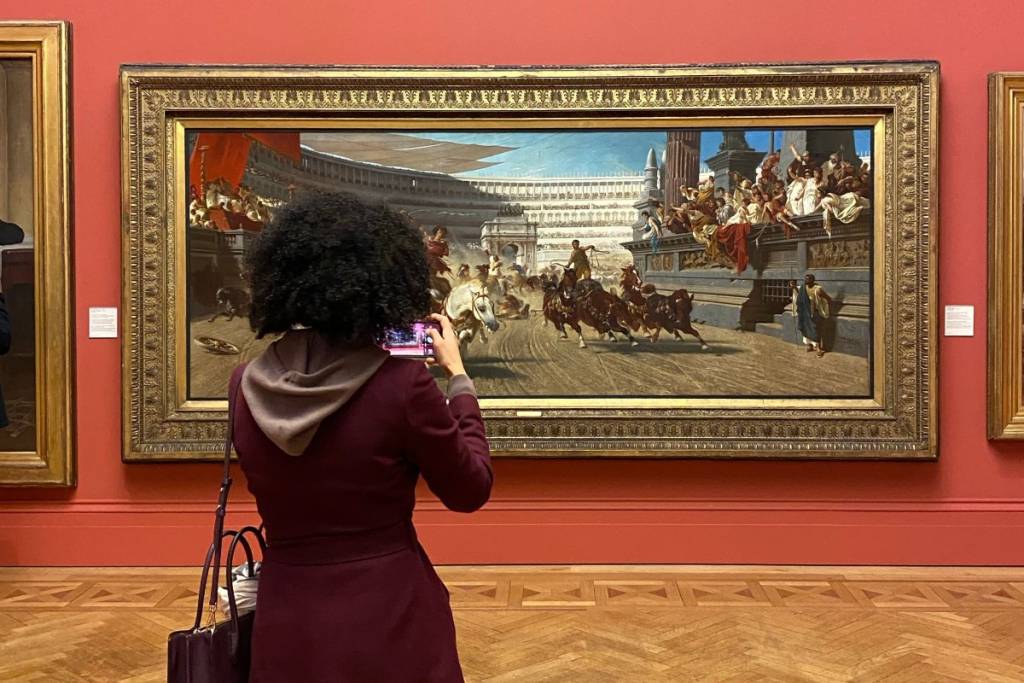 Woman photographing painting in a gallery.