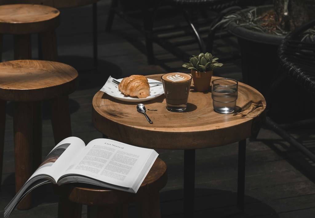 A cafe, croissant and latte on a table, an open book