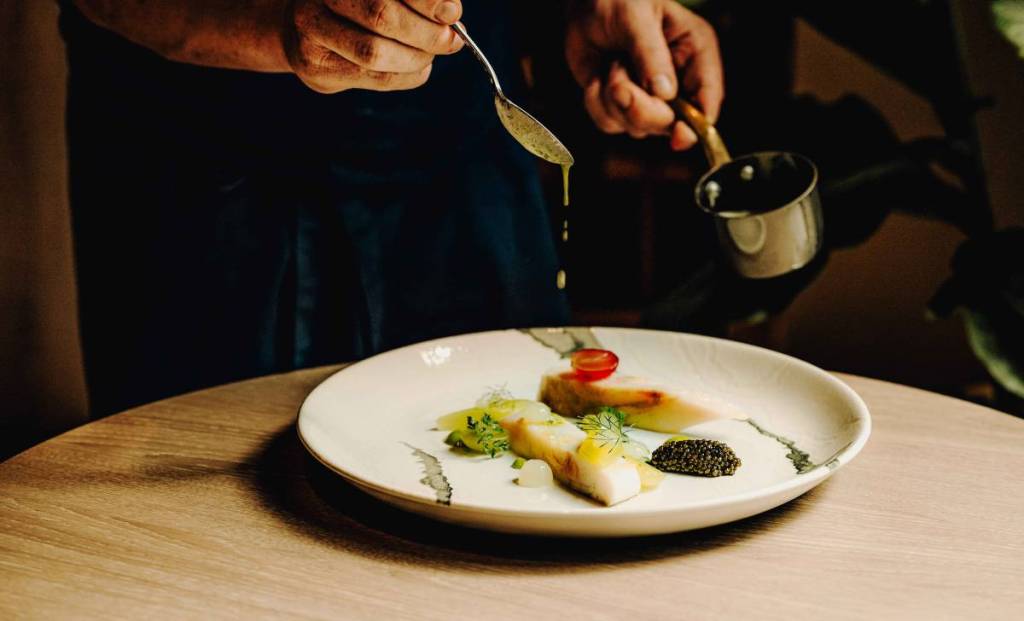 sauce being poured over fish dish