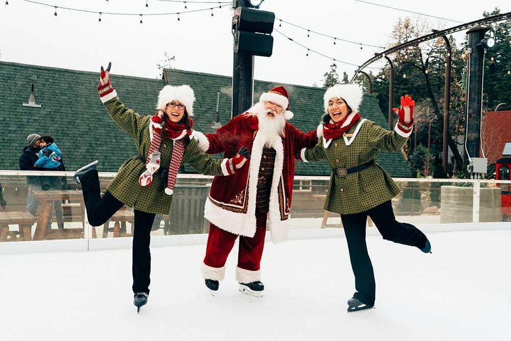two women and father christmas on ice rink