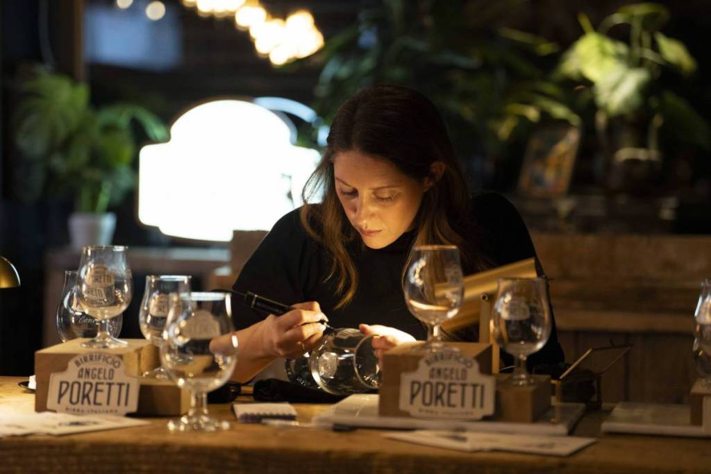 A woman peering closely at a point glass, carving it