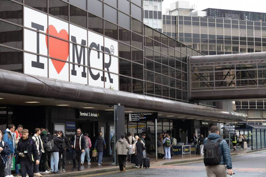 outside manchester airport terminal 3 arrivals with sign saying i love mcr