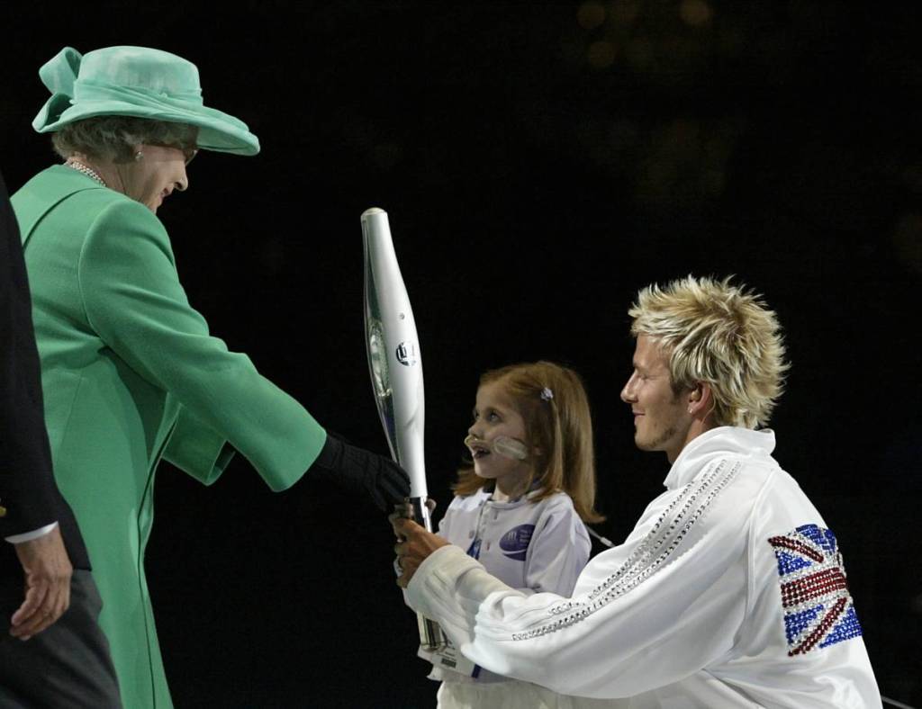 David Beckham of Manchester United and England with Kristy Howard hands the Baton to HM The Queen during the Opening Ceremony at the City of Manchester Stadium during the 2002 Commonwealth Games in Manchester, England on July 25, 2002.