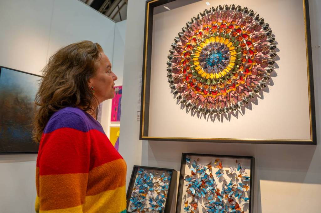 woman in stripey jumper looking at artwork on wall at manchester art fair