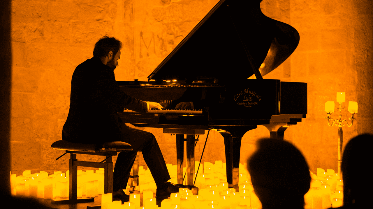 A musician playing the grand piano amid a sea of candles at a Candlelight concert.