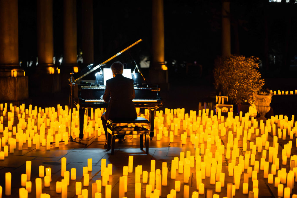 A pianist plays, surrounded by hundreds of candles at a Candlelight concert.