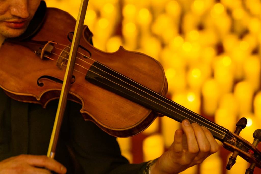violin being played surrounded by hundreds of candles