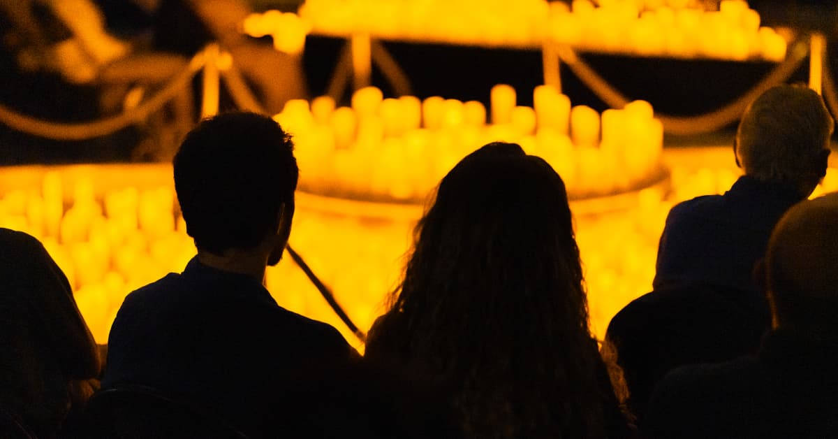 Espectadores miran hacia un escenario cubierto de velas durante un concierto Candlelight.