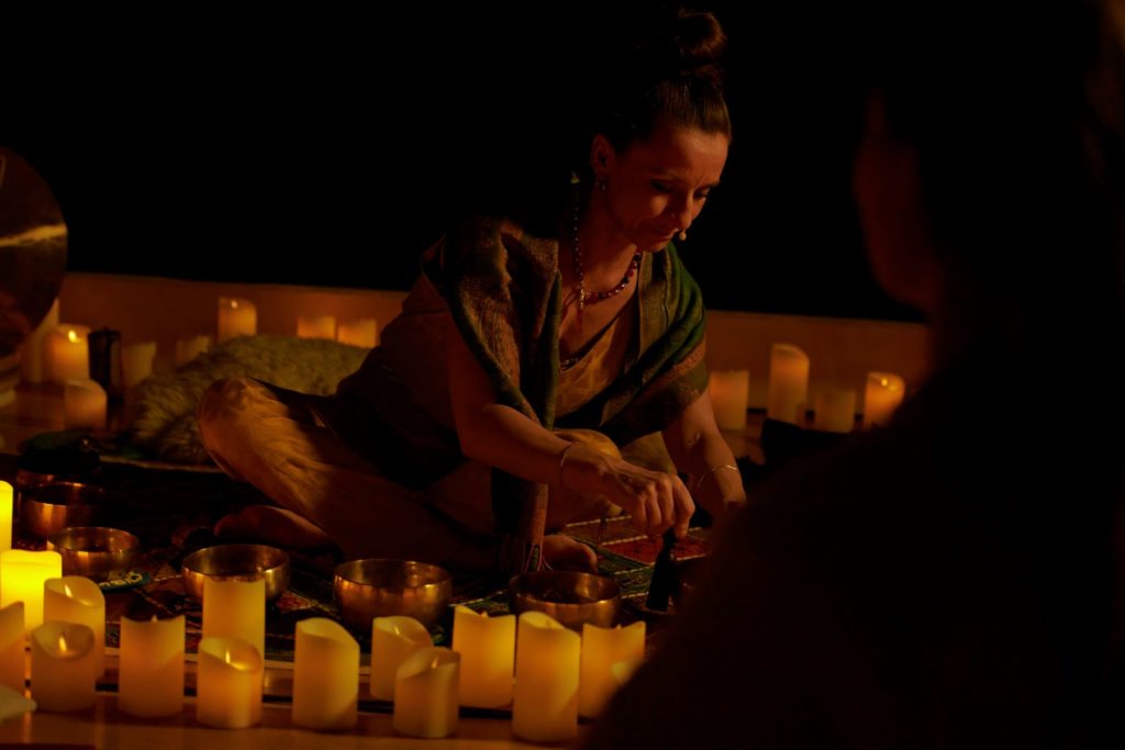 The instructor of the Mindful Glow experience sitting on the ground surrounded by candles.