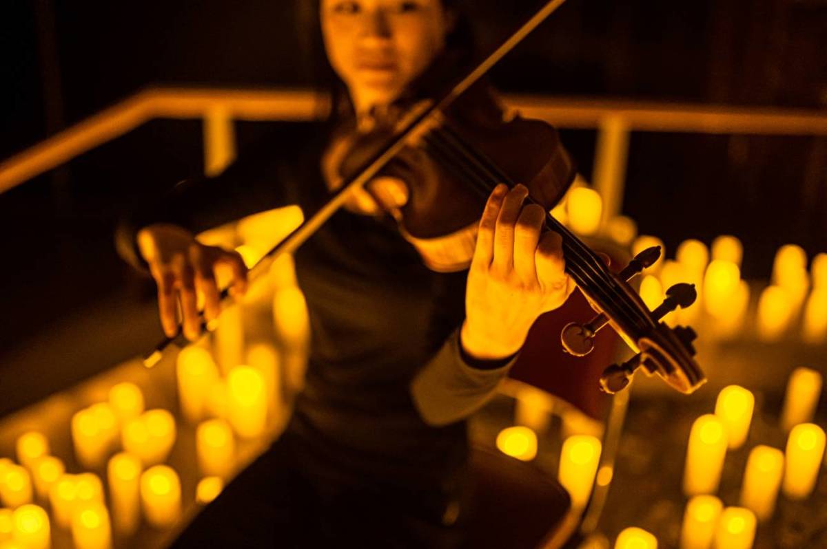 Women plays violin with candles around here