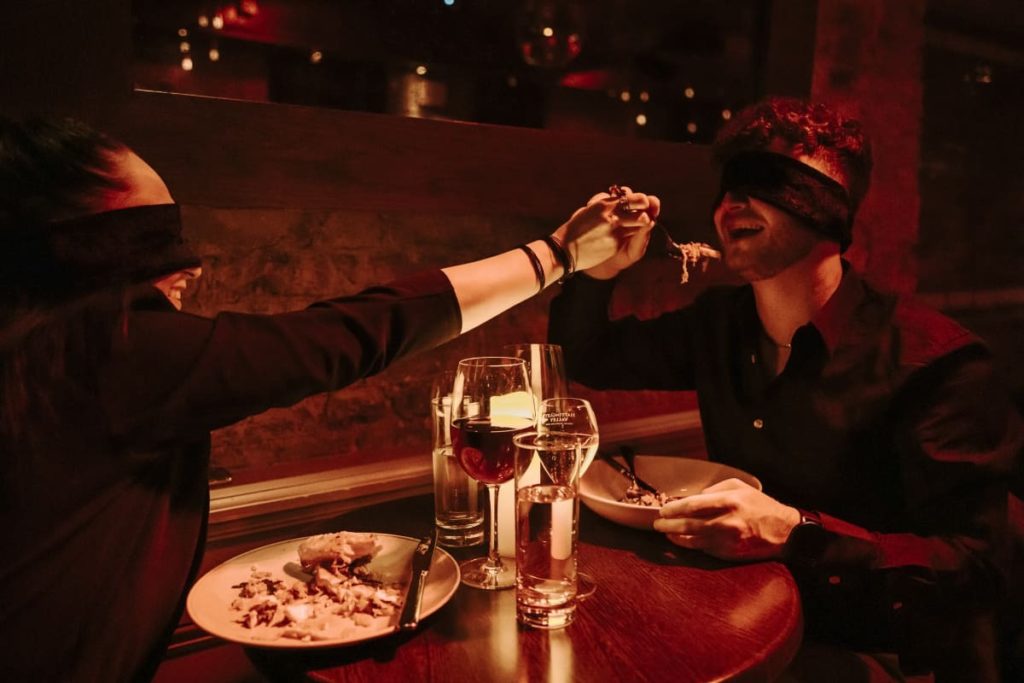 A person feeds another at Dining in the Dark.