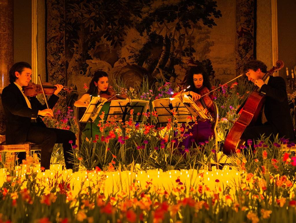 A string quartet performing a Candlelight Spring concert surrounded by both flowers and candles.