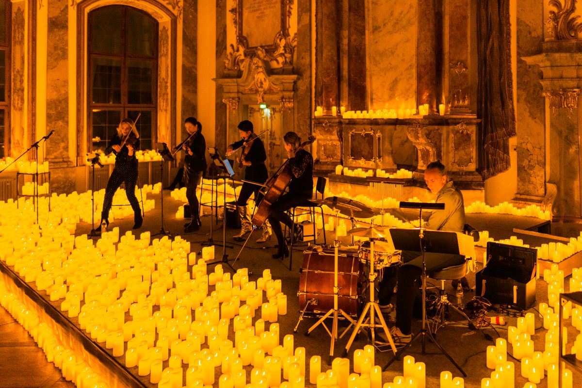 Candlelight-Konzert im Kleinen Goldenen Saal in Augsburg, Streichquartett spielt zusammen mit Schlagzeuger auf der Bühne, umringt von Kerzen