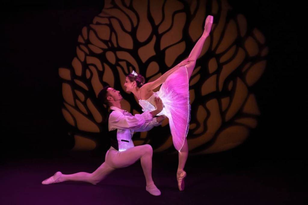 Two ballet dancers perform in glowing costumes at Ballet of Lights.