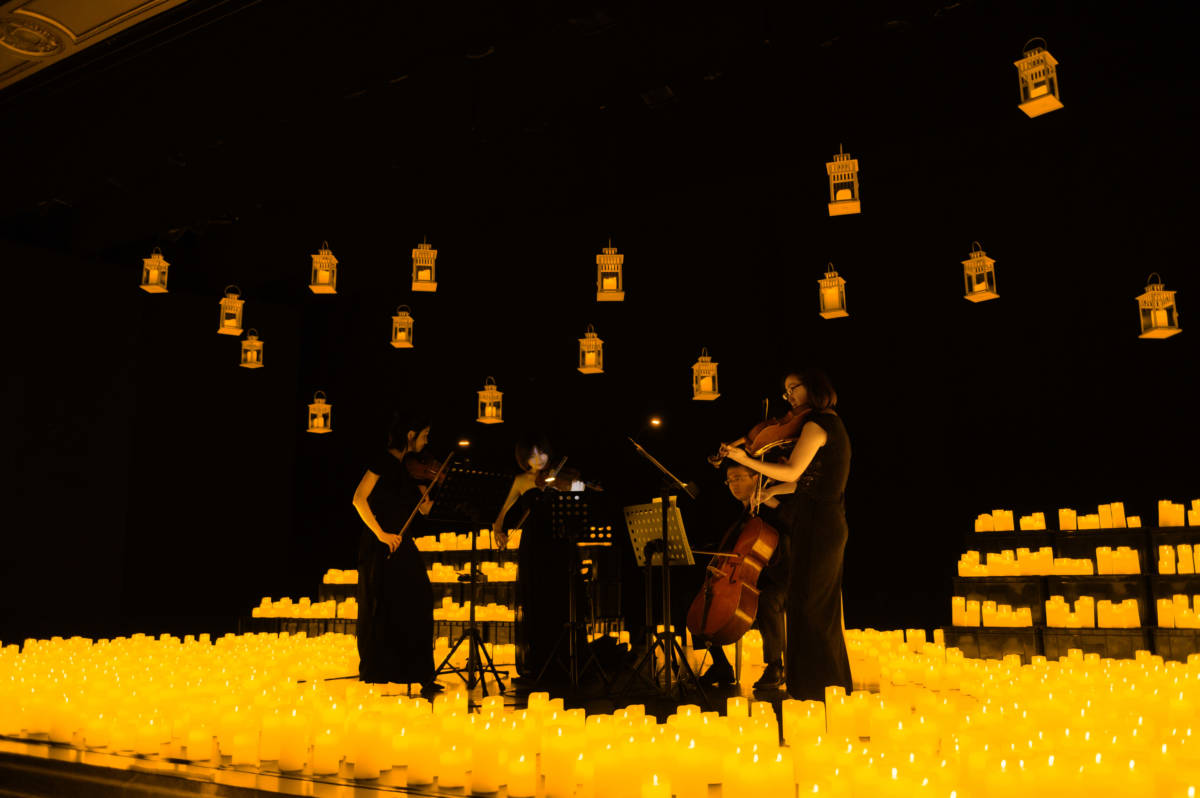 A string quartet plays on a candlelit stage during a Candlelight concert.
