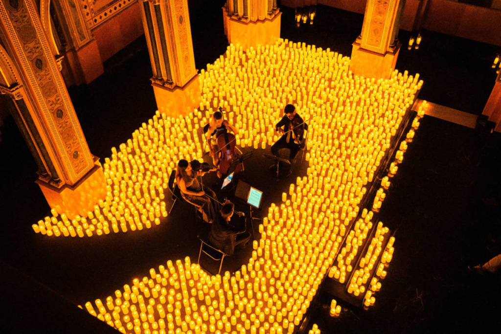 A string quartet plays on a candlelit stage during a Candlelight concert.