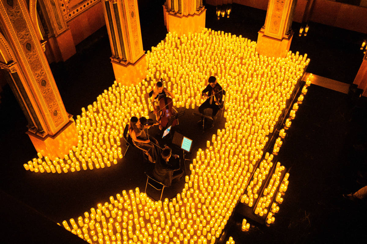 A string quartet plays on a candlelit stage during a Candlelight concert.