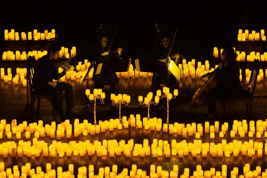 A string quartet plays on a stage covered with warm candles during a Candlelight concert.