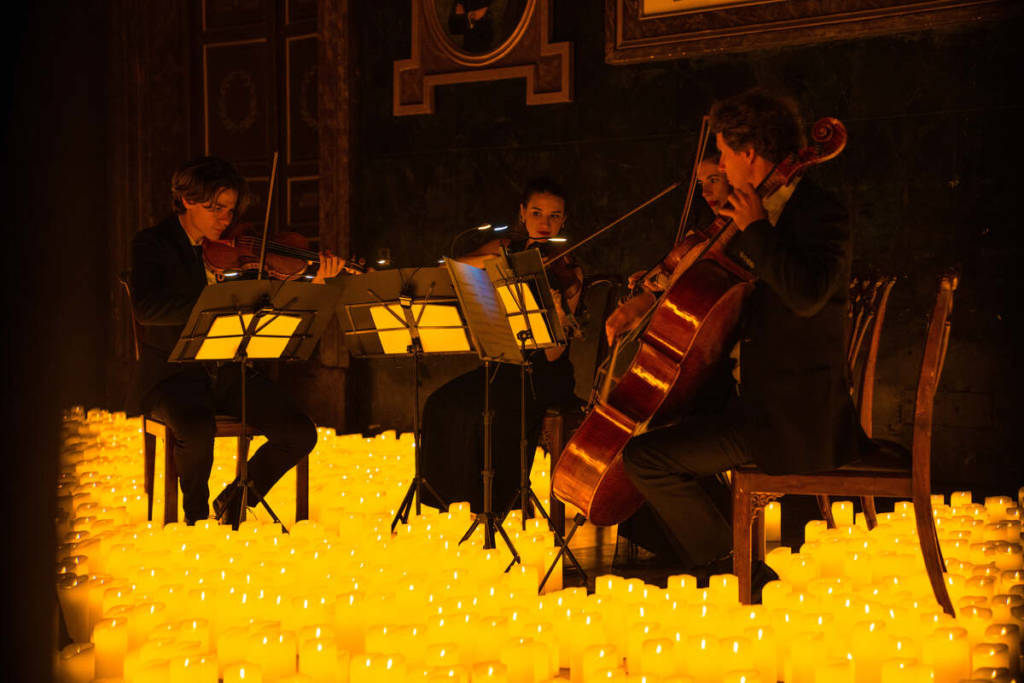 A string quartet performing amid a sea of candles