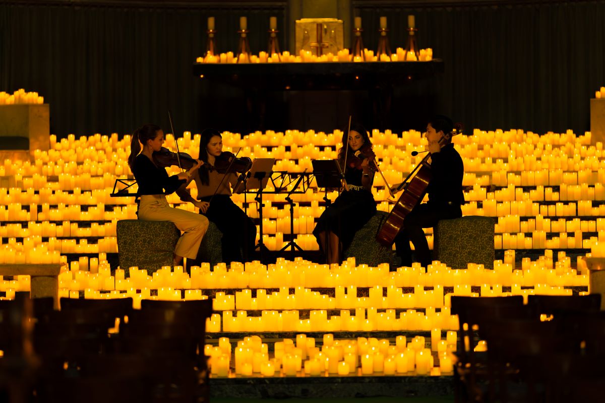 Streichquartett spielt auf der Bühne eines Candlelight-Konzertes, umgeben von zahlreichen Kerzen.