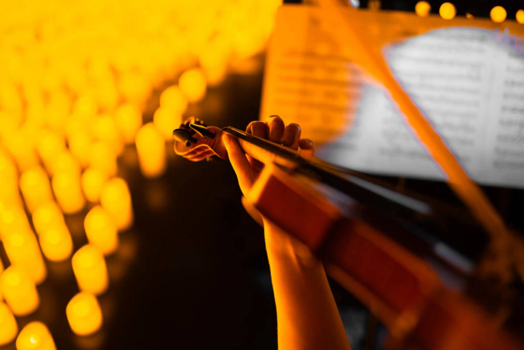 Primer plano de la mano de un violinista durante un concierto Candlelight.