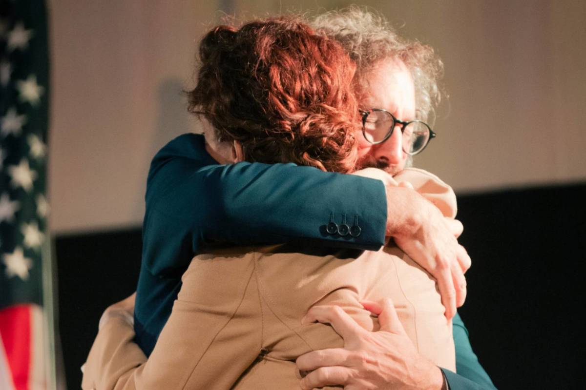 a man and a woman hug with an american flag behind them in an emotional moment as part of the jury experience