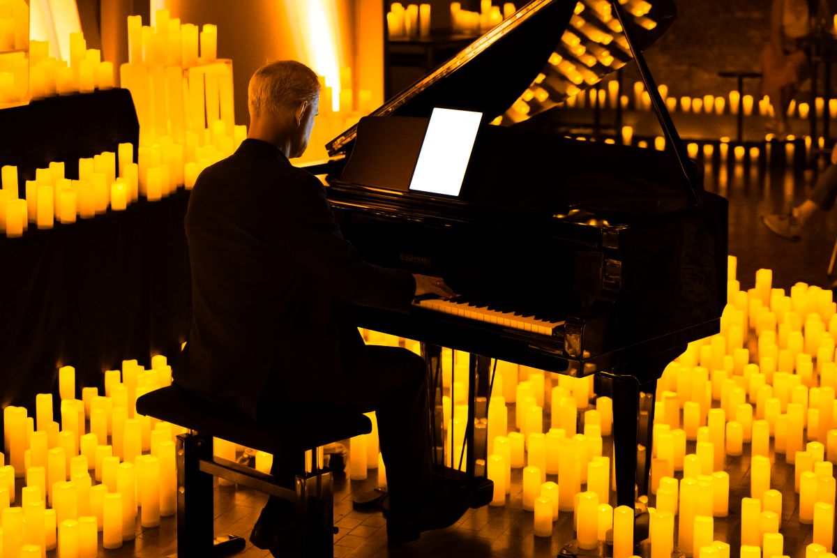 Pianist sitzt an einem Flügel und spielt bei einem Candlelight-Konzert auf der Bühne zwischen zahlreichen Kerzen