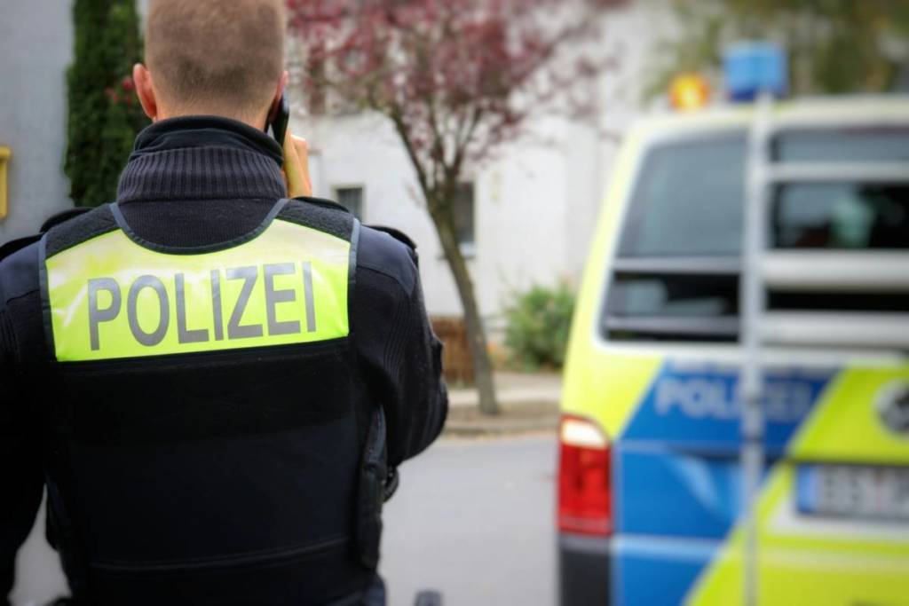 Polizeibeamter in Uniform mit Polizeiauto im Hintergrund