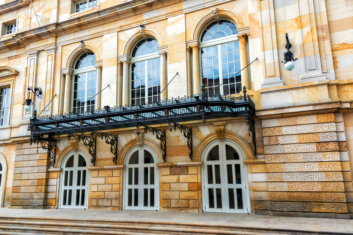 Fachada principal del Teatro Colón de Bogotá, con su estilo neoclásico y detalles en hierro forjado sobre las puertas de acceso.