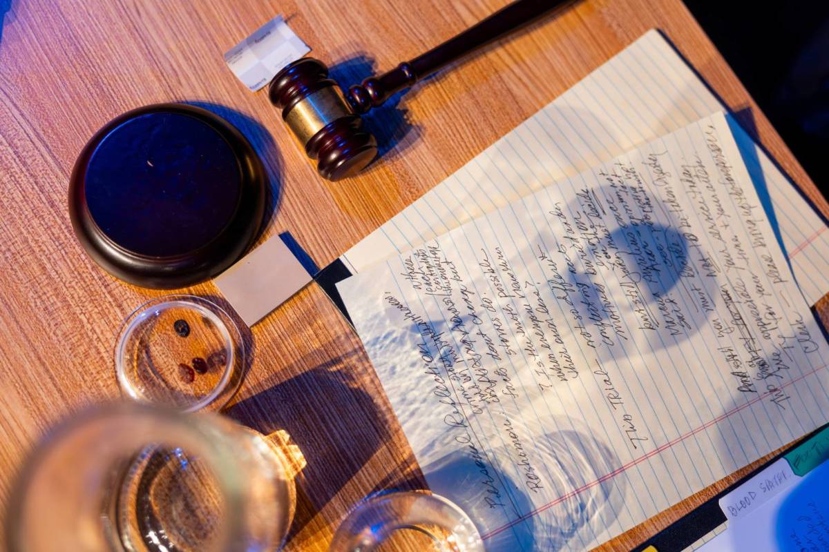 Primer plano del atrezzo de The Jury Experience sobre una mesa de madera: documentos, pruebas y un mazo de juez.