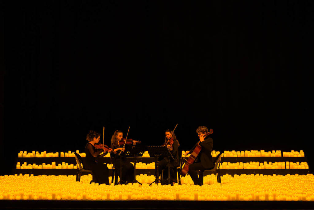 A string quartet performing on stage surrounded by thousands of candles at a Candlelight concert