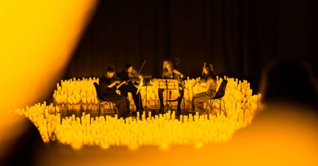 A string quartet performing amid a sea of candles