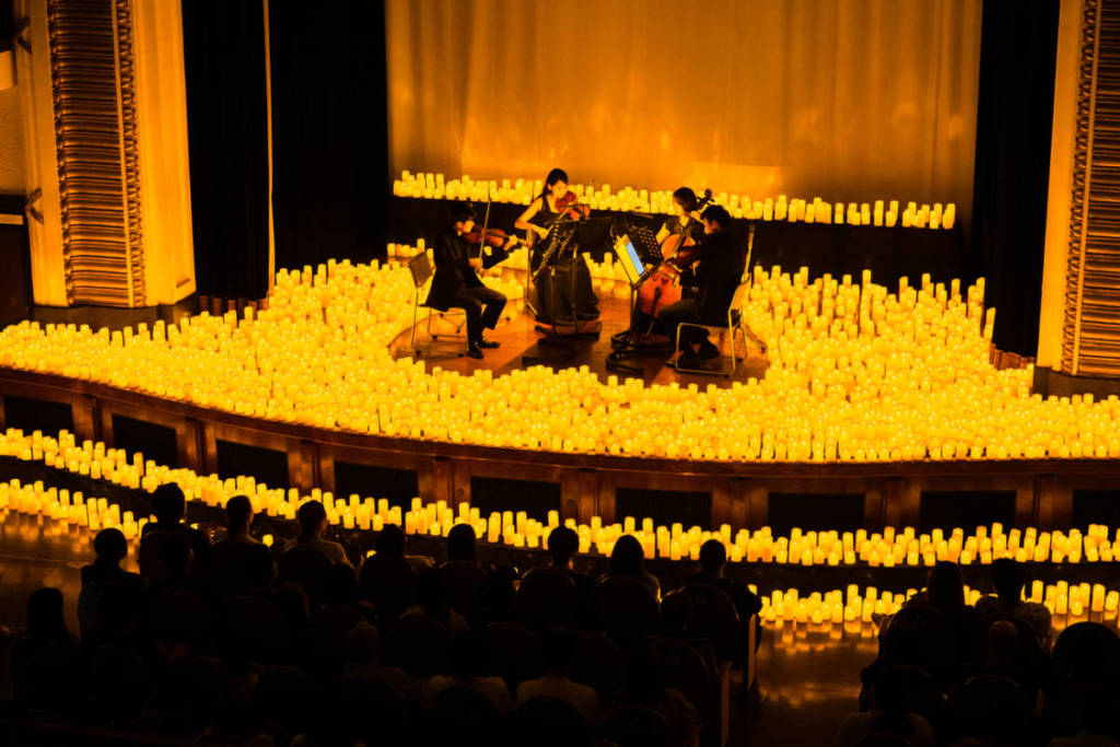 Streichquartett spielt auf der Bühne von Candlelight, umgeben von etlichen Kerzen und Publikum im Vordergrund