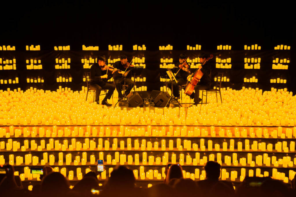Streichquartett spielt auf der Bühne von Candlelight, umgeben von etlichen Kerzen und Publikum im Vordergrund