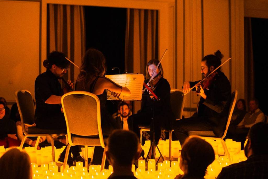 A string quartet performing amid a sea of candles