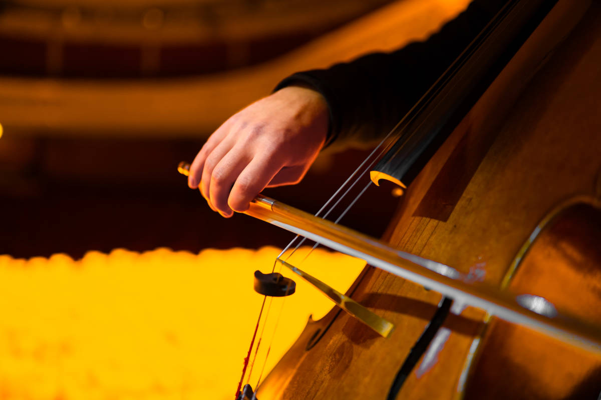 Un musicista suona un violoncello circondato da un mare di candele durante lo spettacolo Candlelight a Taranto