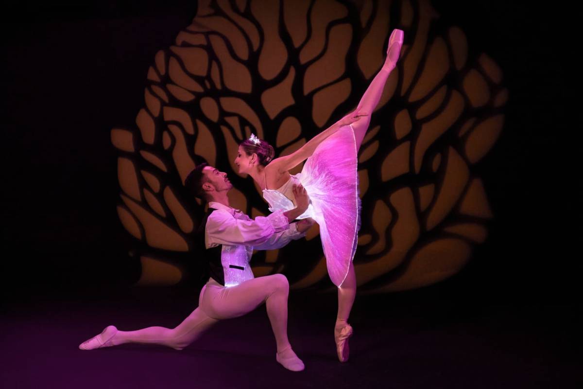 casal de bailarinos de balé com roupas brancas e rosa quase se beijando