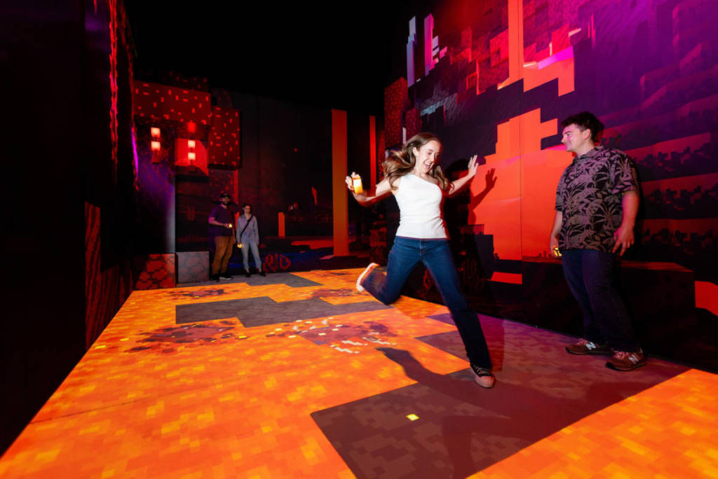 a girl jumps over a digital floor of lava at Minecraft Experience: Villager Rescue
