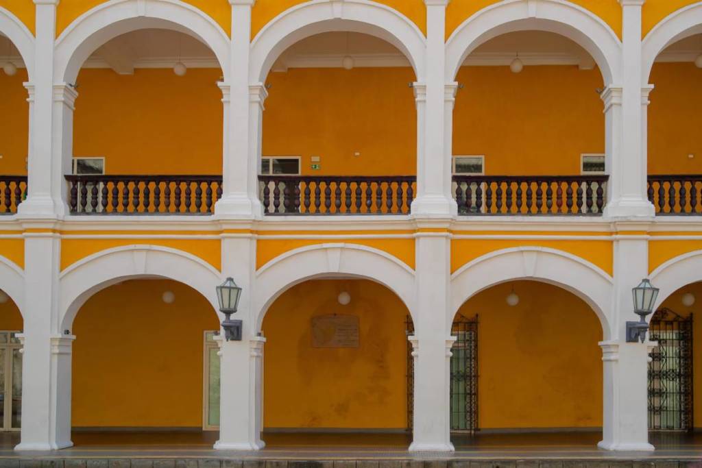 Detalle de la fachada del Palacio de la Proclamación en Cartagena, con balcones de madera oscura, arcos blancos y muros amarillos característicos del edificio