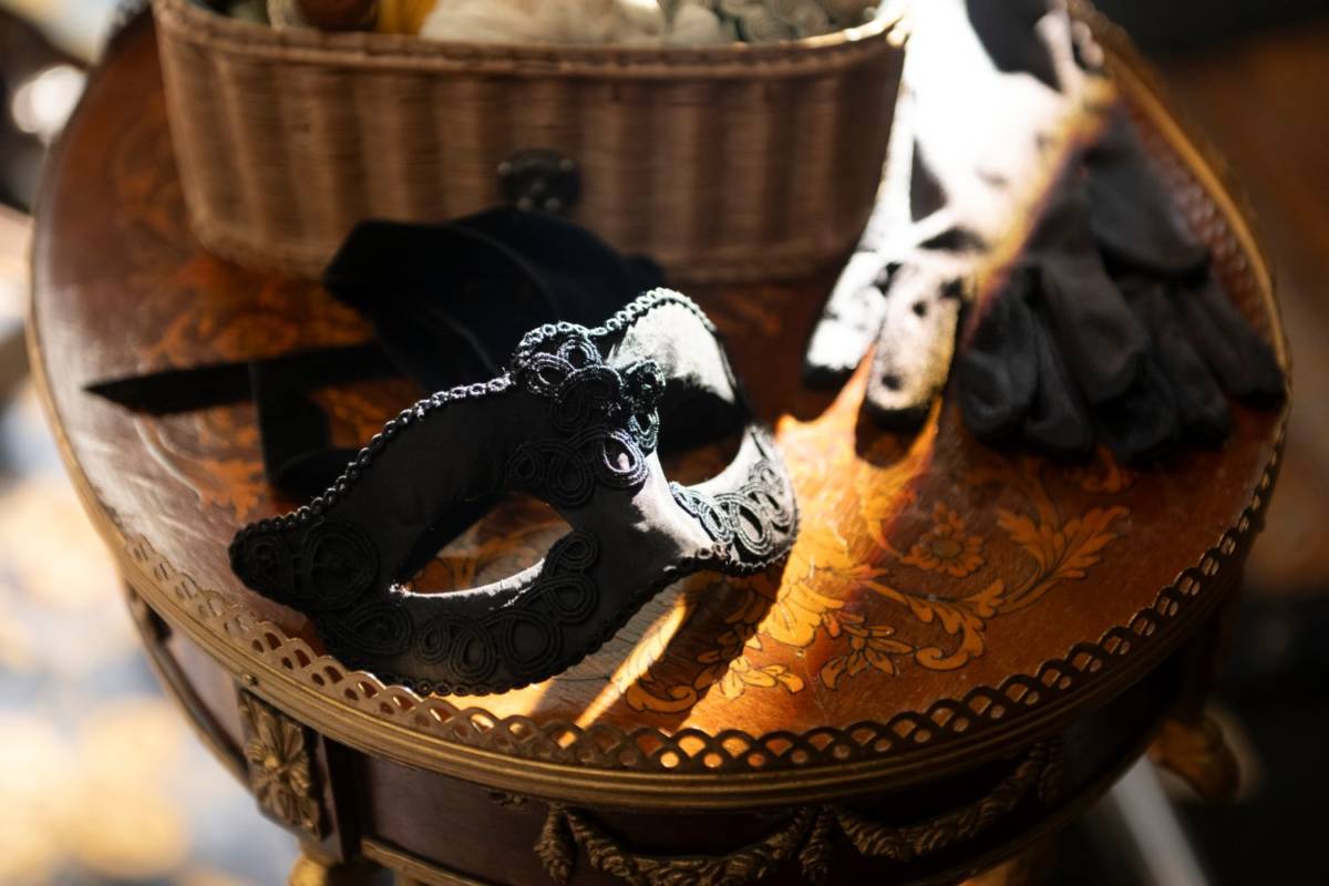 Maske aus "Bridgerton" liegt auf einem Tisch und wird von der Sonne angestrahlt