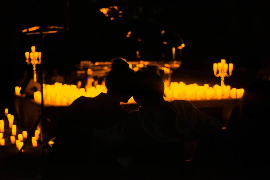 The silhouette of a couple enjoying a Candlelight concert in front of thousands of candles