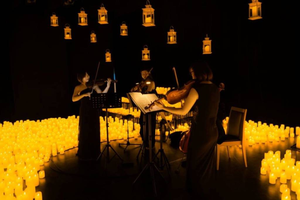 Orchestre jouant autout d'une mer de bougies lors d'un concert Candlelight