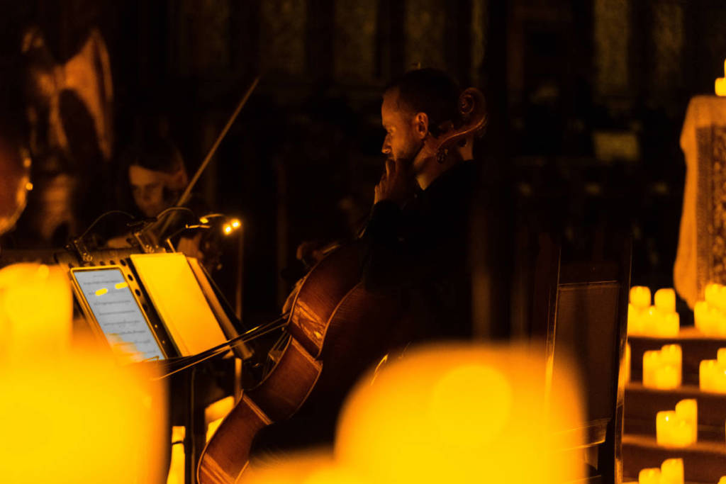 Un violonchelista y una violinista tocan sobre un escenario cubierto de velas durante un concierto Candlelight.