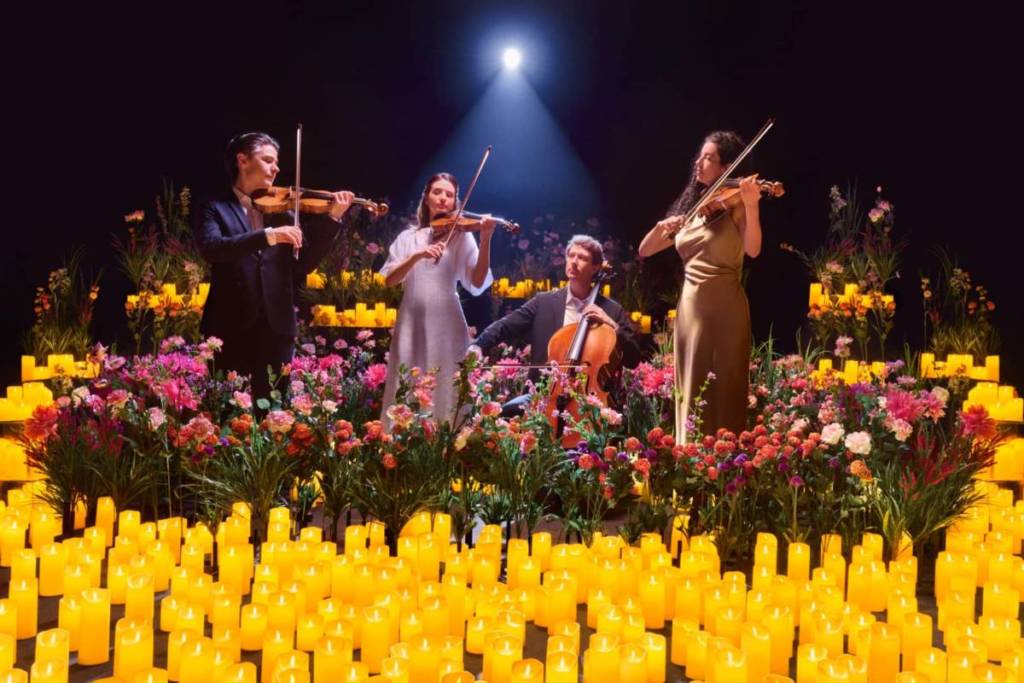 A string quartet plays surrounded by flowers and candles at Candlelight Spring.