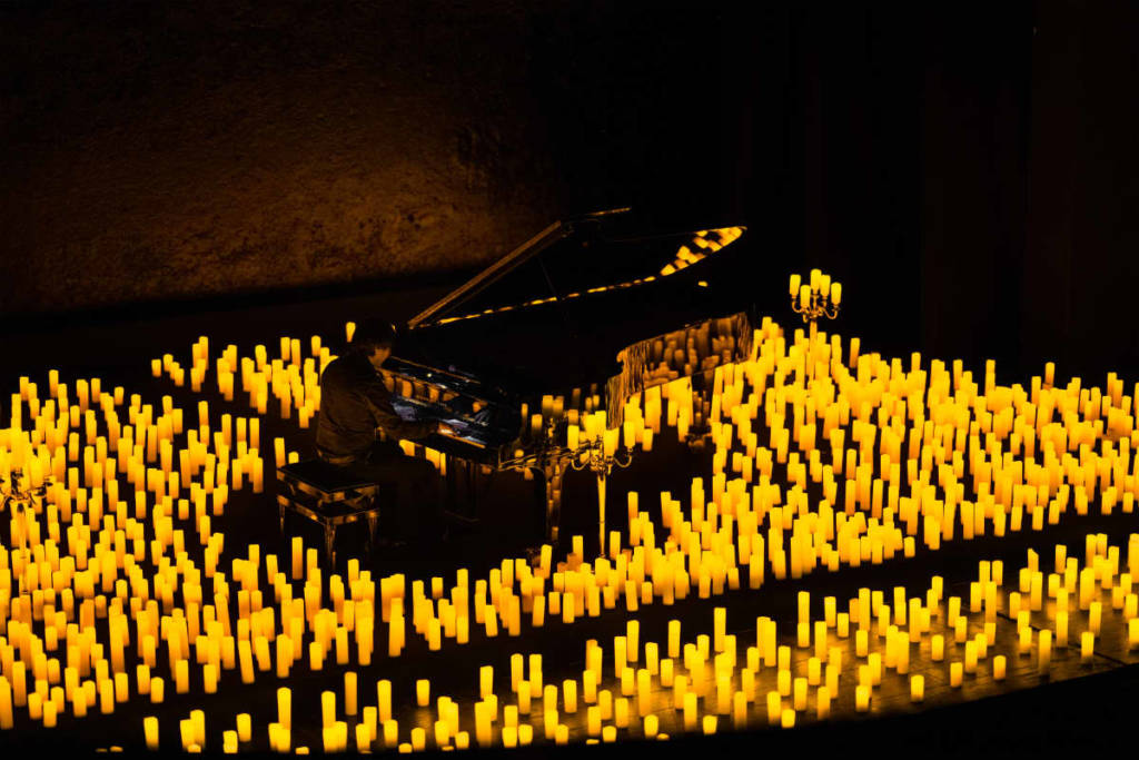 A pianist on stage performing by candlelight